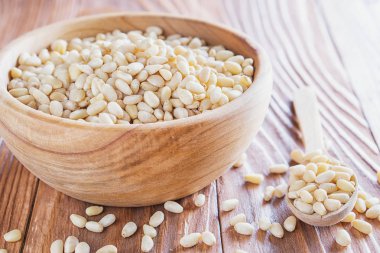 Sedir fındık veya çam fıstığı rustik ahşap zemin üzerinde. Ahşap kase ve kaşık soyulmuş çam fıstığı.