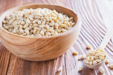 Sedir fındık veya çam fıstığı rustik ahşap zemin üzerinde. Ahşap kase ve kaşık soyulmuş çam fıstığı.