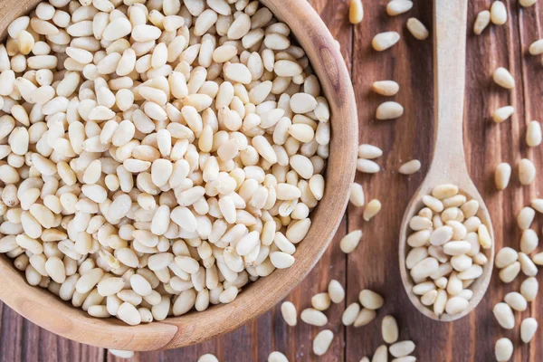 Sedir fındık veya çam fıstığı rustik ahşap zemin üzerinde. Soyulmuş çam fıstığı ahşap kase ve kaşık. Üstten görünüm.