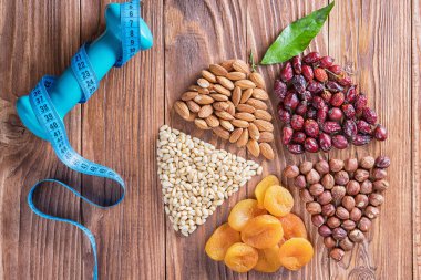 Kuru Kayısı, fındık, ölçüm bandı ve ahşap bir masa üzerinde halter kompozisyon yuvarlak. Daire fındık ve kuru kayısı yapılan bölüme ayrılmıştır. Sağlıklı yaşam kavramı. 