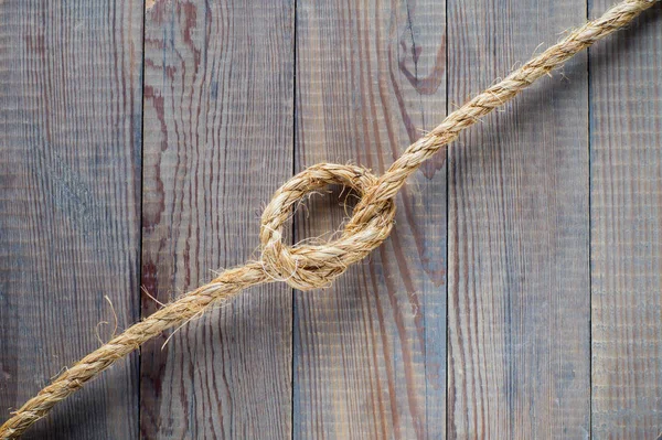 Knot of the rope on the wooden background.  Rope with knot on blank antique brown rustic wood background with copy space.