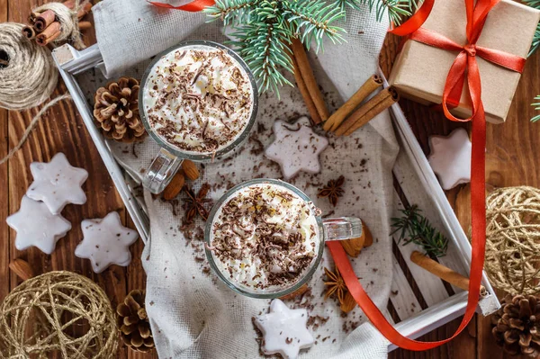 Noel arka plan iki latte, çerezleri yıldız, çam dalları, koniler, hediye ve baharatlar ile. Çift kahve süt ve ev yapımı lezzetli kurabiye tepsisi ahşap arka plan üzerinde. Düz yatıyordu, en iyi görünümü.
