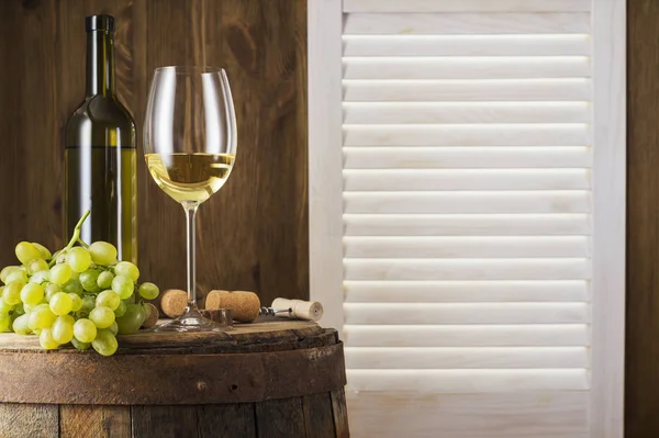 コピー スペースを持つ木製の樽と白ワインの静物 ワインの瓶 白ワインのガラス 古い木樽にブドウの房 ワインの試飲と生産の概念 — ストック写真