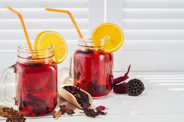 İki meyve çay saman vintage beyaz ahşap kepenkleri arka plan karşı içme ile vintage kavanozların içinde. Vintage mason kavanoz kırmızı buzlu çay, tarçın ve anasonu beyaz pencere eşiğinde