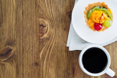 İştah açıcı kek sepeti dilimlenmiş meyve, çilek ve kopya alanı rustik ahşap zemin üzerine kahve. Lezzetli ve taze tatlı ve kahve, üstten görünüm, lay düz. Sabah seçim.