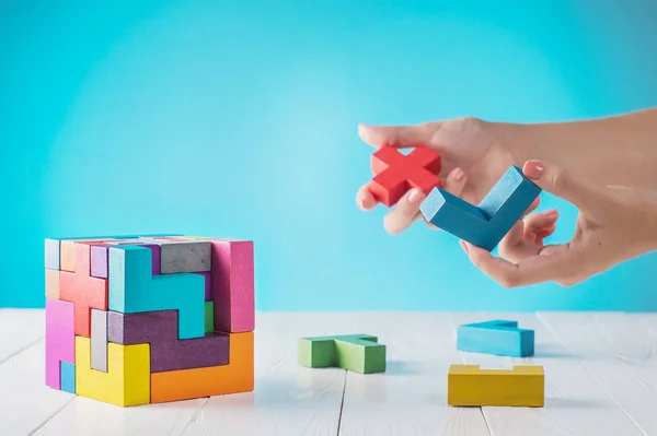 Concept of decision making process, logical thinking. Logical tasks. Conundrum, find the missing piece of the proposed. Hand holding wooden puzzle element. Hand sets the last element of the puzzle.