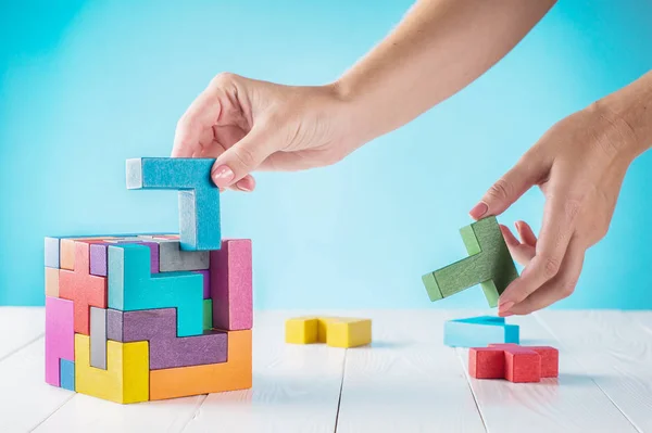 Concept of decision making process, logical thinking. Logical tasks. Conundrum, find the missing piece of the proposed. Hand holding wooden puzzle element. Hand sets the last element of the puzzle.