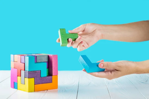 Concept of decision making process, logical thinking. Logical tasks. Conundrum, find the missing piece of the proposed. Hand holding wooden puzzle element. Hand sets the last element of the puzzle.