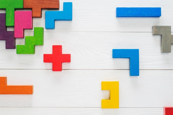 Concept of creative, logical thinking. Different colorful shapes wooden blocks on white wooden background, flat lay, copy space. Geometric shapes in different colors, top view. Abstract Background.