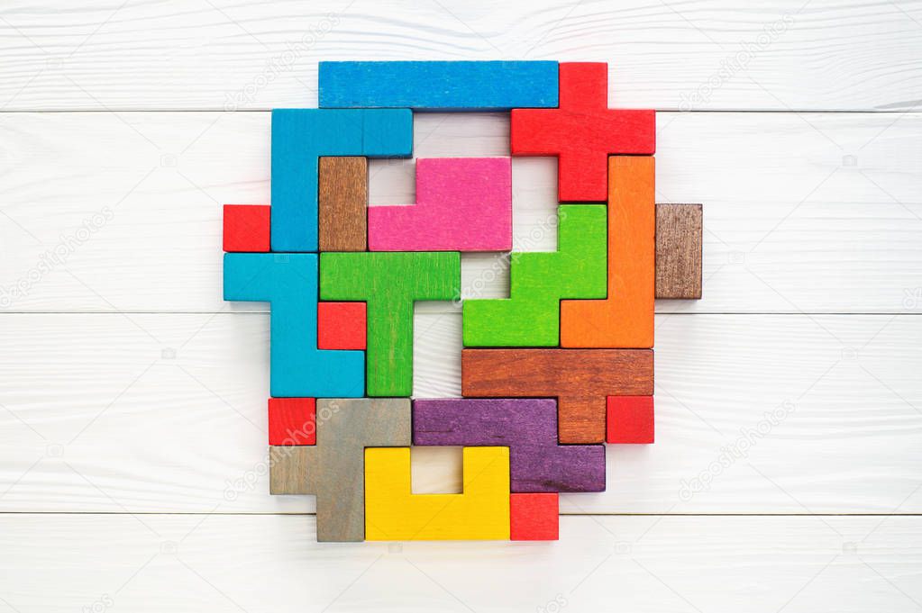 Concept of creative, logical thinking. Different colorful shapes wooden blocks on white wooden background, flat lay, copy space. Abstract question mark made of wooden blocks, top view.