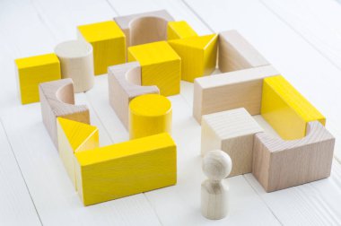 Çeşitli şekiller ahşap bloklar sarı-bej labirent. Labirent önünde dostum. Zor yolu çıkış, iş kavramı bulmak için. Bir strateji, çözümler için arama kavramı.