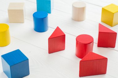 Mantıksal düşünme kavramı. Beyaz ahşap arka plan üzerinde renkli ahşap bloklar. Geometrik şekiller - küp, üçgen prizma, silindir ahşap arka plan üzerinde. Mantıksal düşünme kavramı.