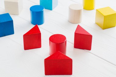 Beyaz ahşap arka plan üzerinde renkli ahşap bloklar. Yaratıcılık oyuncaklar. Çocuk yapı taşları. Geometrik şekiller - küp, üçgen prizma, silindir. Mantıksal düşünme kavramı.