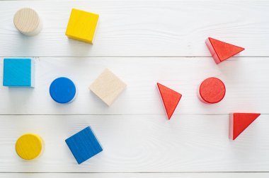 Üstten görünüm, beyaz arka plan üzerinde renkli ahşap blokları lay düz. Çocukların yaratıcılık oyuncakları. Geometrik şekiller - küp, üçgen prizma, silindir. Mantıksal düşünme kavramı.
