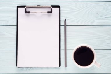 Klasör, pano ile beyaz boş kağıt sayfası, kalem ve kopya alanı, üstten görünüm ile kahve. İş kavramı. Boş pano, düz ahşap arka plan üzerinde yatıyordu.