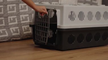 Tanınmamış kişiler, evcil hayvan kafesini açar. Yolculuk için hazırlarken detaylara dikkat ederler. Taşınabilir evcil hayvan taşıyıcısının nasıl kullanılacağını gösterme.