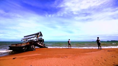 Plaj ve balıkçılık olan turistler silüeti batık gemi kalıntıları.