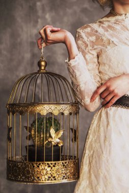 woman in a white lace dress holding a golden cage with gold birds and a cactus. no face psychology therapy concept. women empowerment, golden cage syndrome. entrapment Stockholm syndrome. girl power clipart