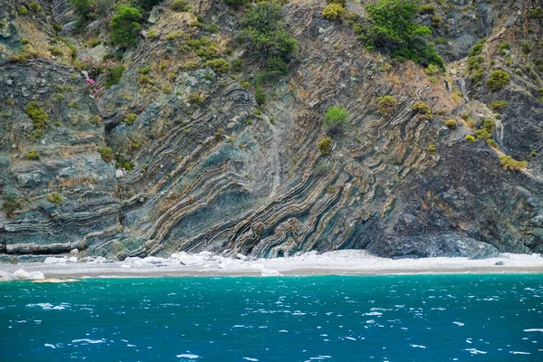 Geologiska berg i Egeiska havet. lager av steniga fossila kusten. Grönska växer på klipporna nära det blå havet. Jordens tillväxtstruktur i lager i Medelhavsområdet — Stockfoto
