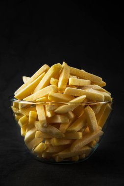 Donmuş patates kızartması ve buzla kaplı cam bir kase. Donmuş fast food patates ürünü. Yarı bitmiş gıda korunumu. Soğuk dondurucu. Koyu dikey seçici yumuşak odaklanma. stüdyo 
