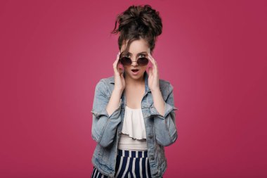 Güneş gözlüklü genç bir şık kız mağaza ürünler indirimler boyutunu tarafından şok. Metin için yer ile izole bir pembe üzerinde duruyor.