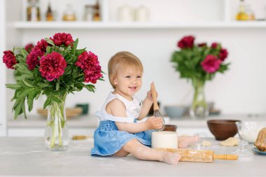Küçük bir çocuk büyük bir ışık mutfakta masada oturur ve un ve hamur ile çalış