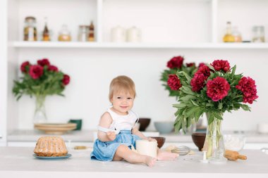 Küçük bir çocuk büyük bir ışık mutfakta masada oturur ve un ve hamur ile çalış