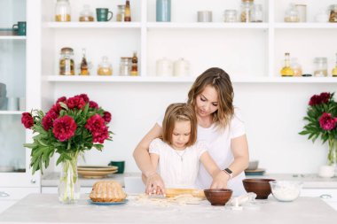 Anne ve küçük kızı büyük bir parlak mutfak oturma ve sağlıklı bir kahvaltı hazırlanıyor
