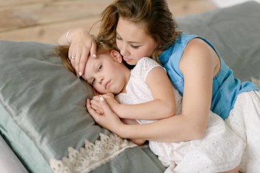 Annem hasta bir küçük kızı yatakta yatıyordu kucaklayan