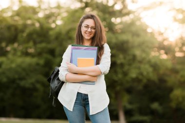 Notebook ve kulakları için çevrimiçi bir konferans dinlerken kulaklık ile bir klasör olan bir genç kız öğrenci. O onun anadil metin çevirir ve sınavları için hazırlar