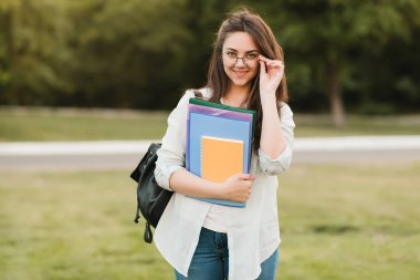Notebook ve kulakları için çevrimiçi bir konferans dinlerken kulaklık ile bir klasör olan bir genç kız öğrenci. O onun anadil metin çevirir ve sınavları için hazırlar