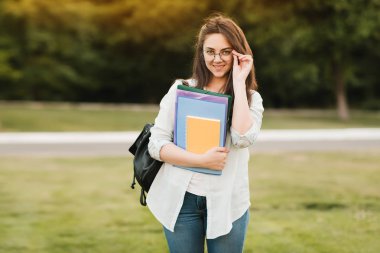 Notebook ve kulakları için çevrimiçi bir konferans dinlerken kulaklık ile bir klasör olan bir genç kız öğrenci. O onun anadil metin çevirir ve sınavları için hazırlar