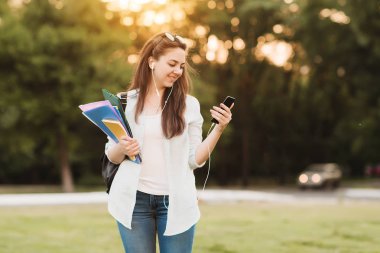 Notebook ve kulakları için çevrimiçi bir konferans dinlerken kulaklık ile bir klasör olan bir genç kız öğrenci. O onun anadil metin çevirir ve sınavları için hazırlar