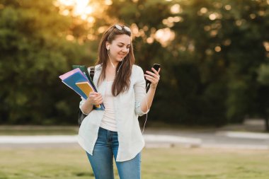Notebook ve kulakları için çevrimiçi bir konferans dinlerken kulaklık ile bir klasör olan bir genç kız öğrenci. O onun anadil metin çevirir ve sınavları için hazırlar