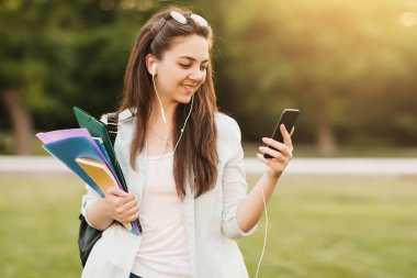 Notebook ve kulakları için çevrimiçi bir konferans dinlerken kulaklık ile bir klasör olan bir genç kız öğrenci. O onun anadil metin çevirir ve sınavları için hazırlar