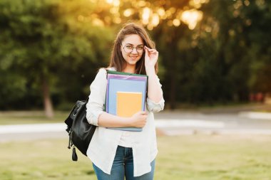 Notebook ve kulakları için çevrimiçi bir konferans dinlerken kulaklık ile bir klasör olan bir genç kız öğrenci. O onun anadil metin çevirir ve sınavları için hazırlar