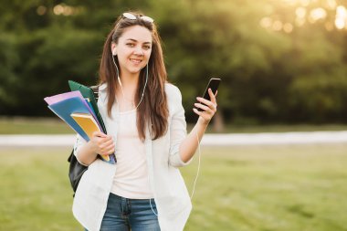 Notebook ve kulakları için çevrimiçi bir konferans dinlerken kulaklık ile bir klasör olan bir genç kız öğrenci. O onun anadil metin çevirir ve sınavları için hazırlar