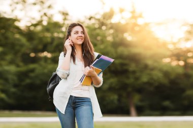 Notebook ve kulakları için çevrimiçi bir konferans dinlerken kulaklık ile bir klasör olan bir genç kız öğrenci. O onun anadil metin çevirir ve sınavları için hazırlar