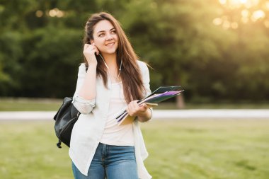 Notebook ve kulakları için çevrimiçi bir konferans dinlerken kulaklık ile bir klasör olan bir genç kız öğrenci. O onun anadil metin çevirir ve sınavları için hazırlar