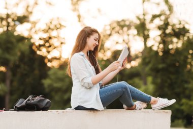 Notebook ve kulakları için çevrimiçi bir konferans dinlerken kulaklık ile bir klasör olan bir genç kız öğrenci. O onun anadil metin çevirir ve sınavları için hazırlar