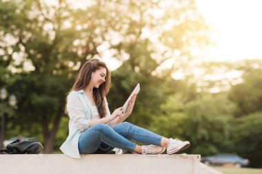 Notebook ve kulakları için çevrimiçi bir konferans dinlerken kulaklık ile bir klasör olan bir genç kız öğrenci. O onun anadil metin çevirir ve sınavları için hazırlar