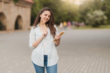 Bir defter ve bir kalem onun elinde genç bir kızla ödevini çözme. notlar not defteri için yazıyor