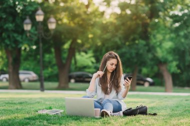 Notebook ve kulakları için çevrimiçi bir konferans dinlerken kulaklık ile bir klasör olan bir genç kız öğrenci. O onun anadil metin çevirir ve sınavları için hazırlar
