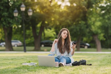 Notebook ve kulakları için çevrimiçi bir konferans dinlerken kulaklık ile bir klasör olan bir genç kız öğrenci. O onun anadil metin çevirir ve sınavları için hazırlar