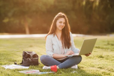 Notebook ve kulakları için çevrimiçi bir konferans dinlerken kulaklık ile bir klasör olan bir genç kız öğrenci. O onun anadil metin çevirir ve sınavları için hazırlar