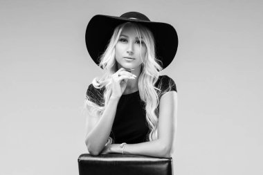 Genç Sarışın kadın büyük siyah şık şapka ve siyah elbise çerçeve içine bakıyor. O temiz ve sağlıklı bir cilt, ciddi bir göz vardır