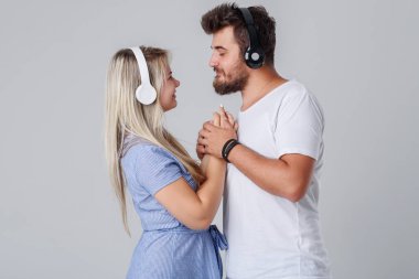 Kablosuz kulaklık, gri bir arka planda gülümseyen ile genç ve neşeli neşeli çift. Club Djs