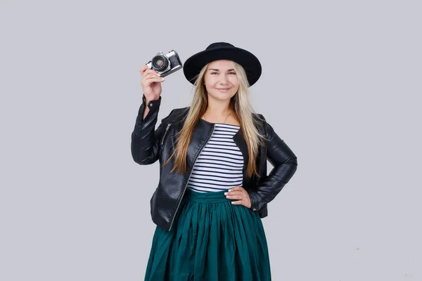 ファッションを見て レトロなフィルム カメラで満足しているクールな若い女性モデル写真になります 灰色の背景の上身に着けているエレガントな帽子 黒のジャケット ブロンディー髪アウトドア — ストック写真