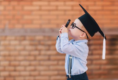 Gözlükler ve akademik şapka bir okul duvara Beka ayakta içindeki küçük çocuk. Büyüteç Camı tutan ve çevre çalışmaları