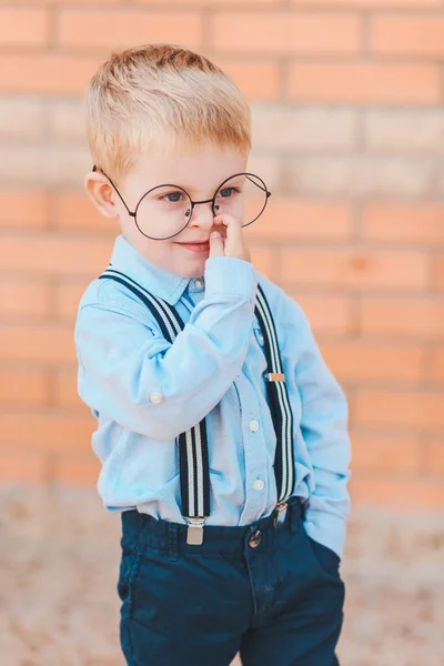 学校に戻る幸せな小さな少年がバックパックや学校の建物のレンガの壁に対して書籍のメガネ — ストック写真